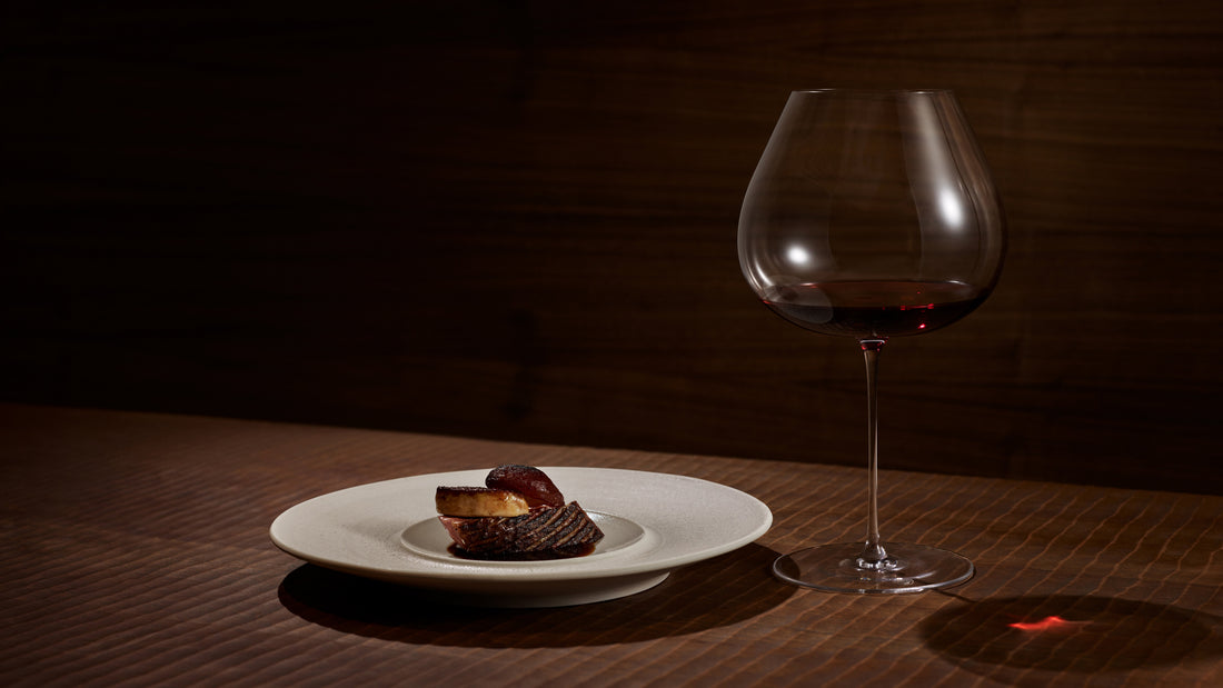 large red wine glass in mood lighting next to a nicely plated dish of food