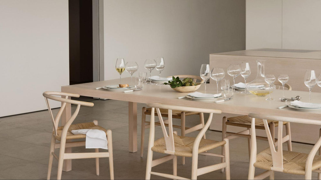 light wood table and chairs with a clean modern table setting with crystal glasses and carafes