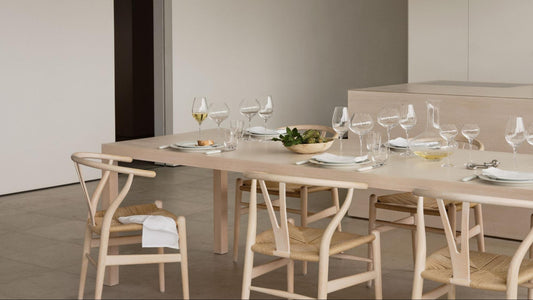 light wood table and chairs with a clean modern table setting with crystal glasses and carafes