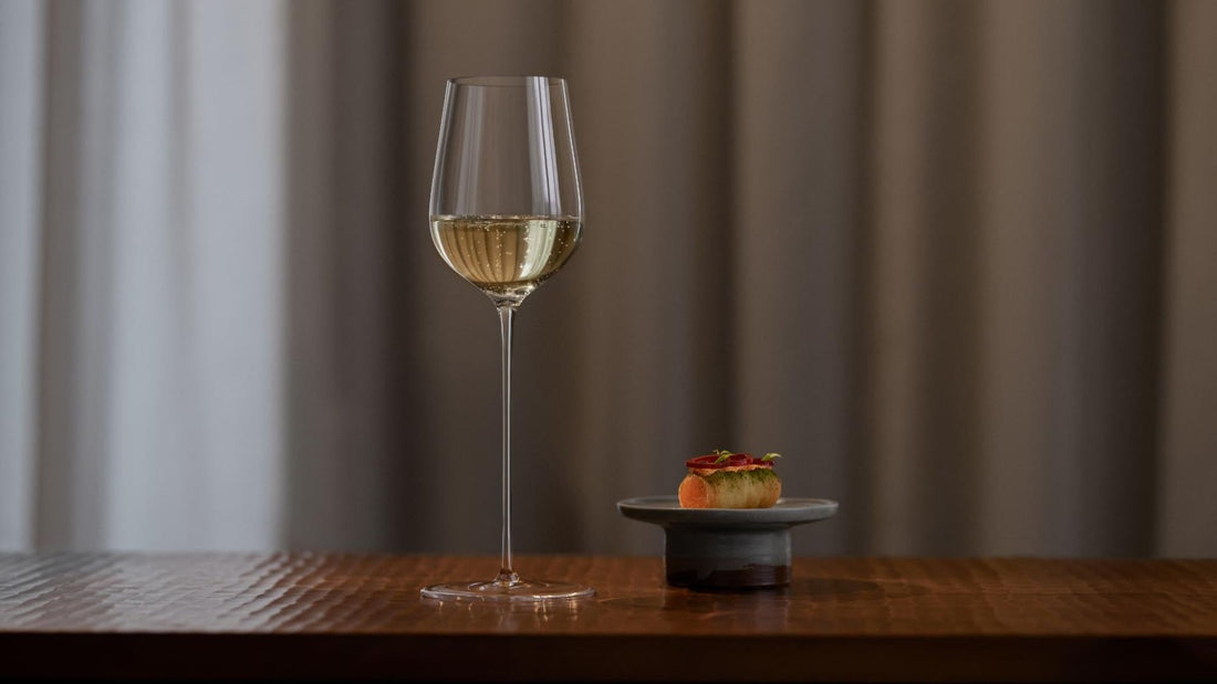 elegant stemware glass on wood table beside small plate of food