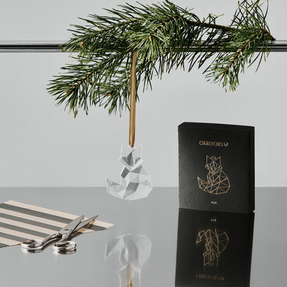 Orreforss crystal fox ornament hanging from a gold ribbon with a black box featuring a fox design on a reflective surface.