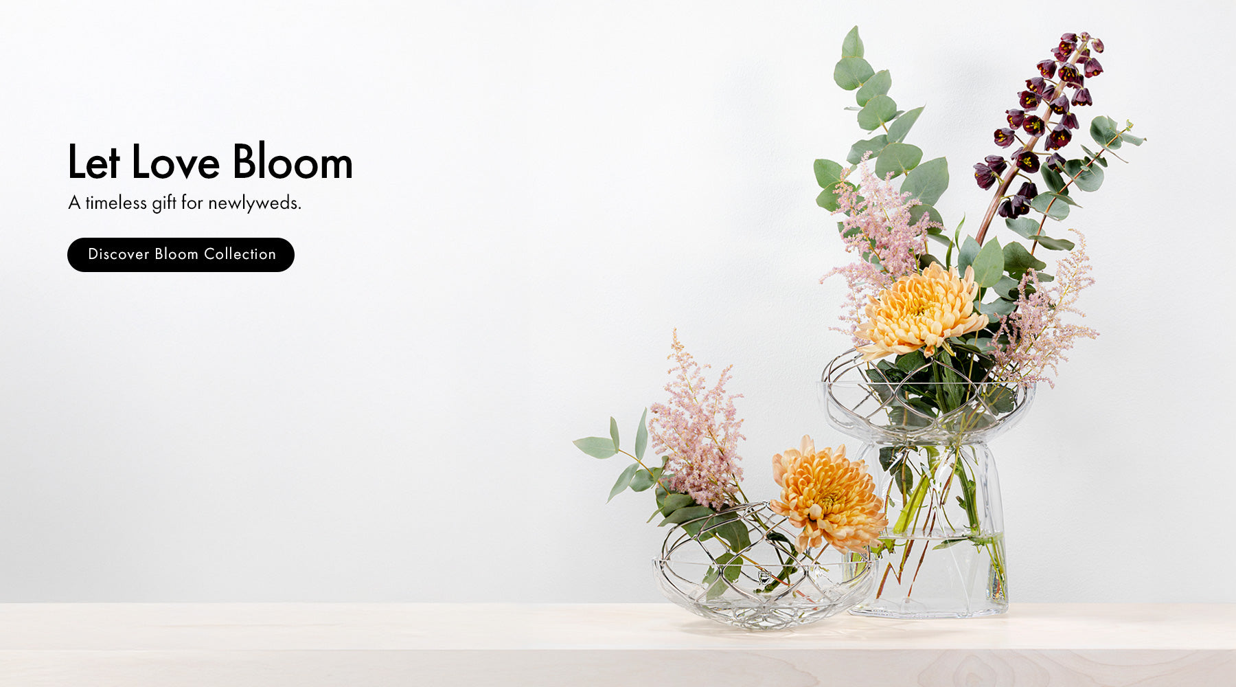 Bloom Collection vases with floral arrangement on a wood surface with neutral background.