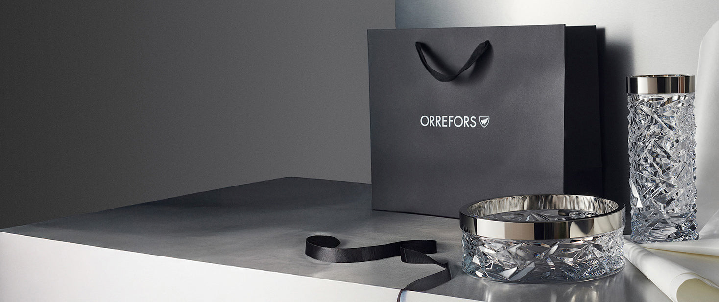 Orrefors Carat collection crystal bowl, vase and Orrefors gift bag, ribbon and tissue on a gray surface
